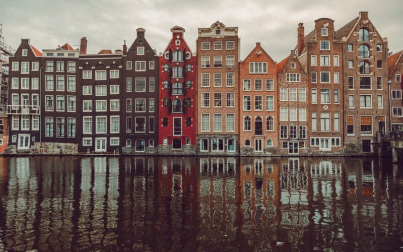 Scenic view of colorful canal houses in Amsterdam with water reflections, capturing urban architecture.