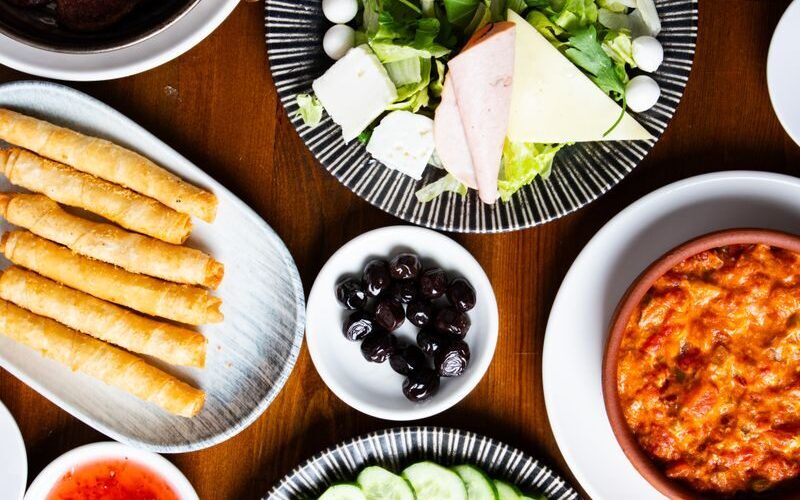 Top view of a vibrant buffet table with salads, dips, meats, and appetizers.