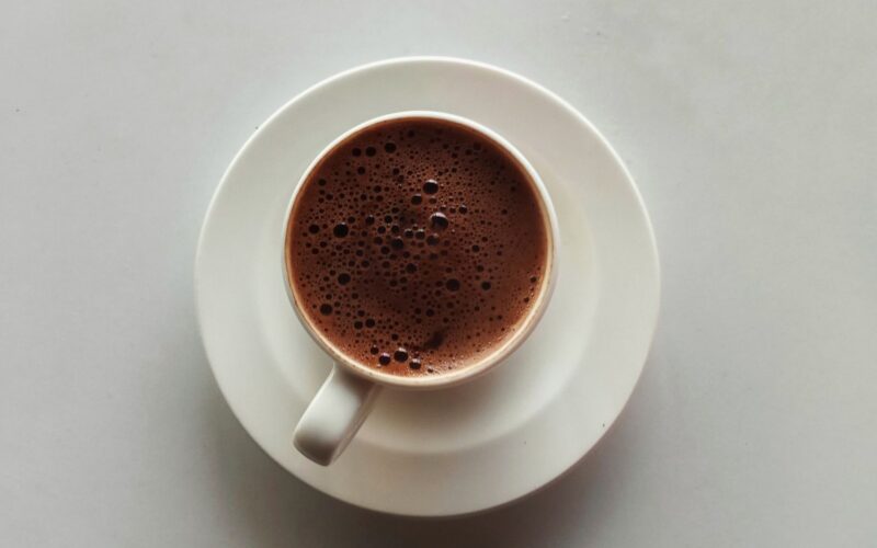A top-down view of espresso coffee with rich foam in a white cup on a saucer.