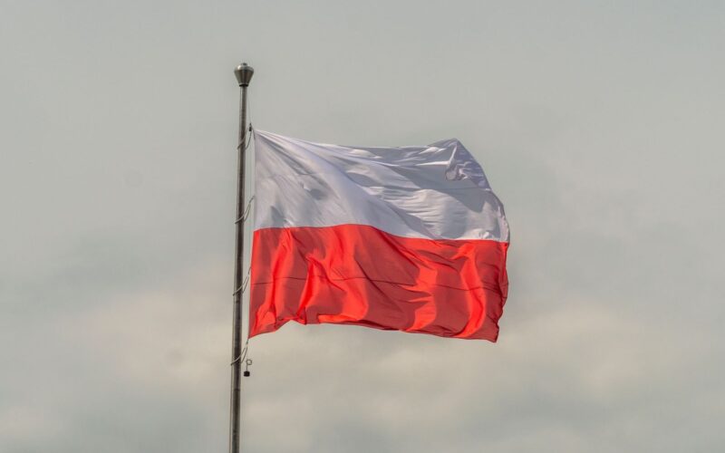 The Polish national flag waving prominently against a cloudy sky, showcasing patriotic pride.
