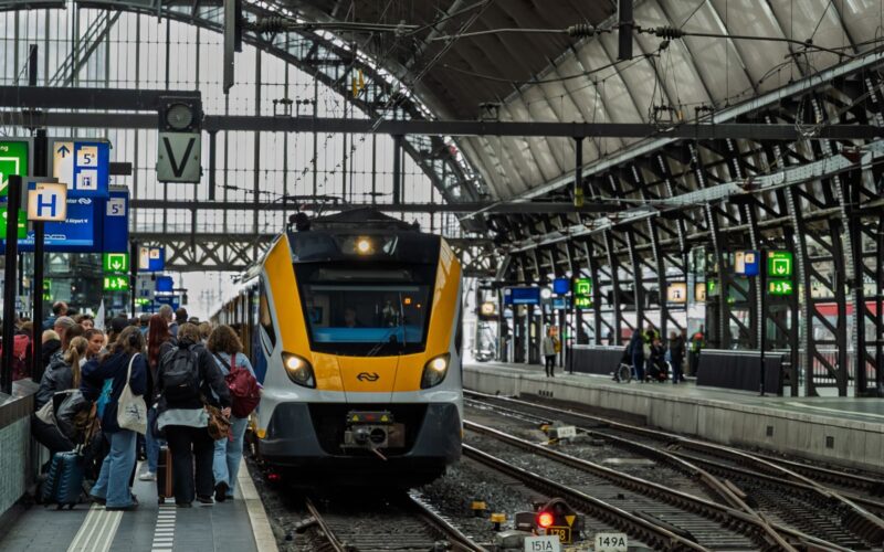 Crowded platform at Amsterdam Central Station with train arriving, capturing daily urban commute scene.