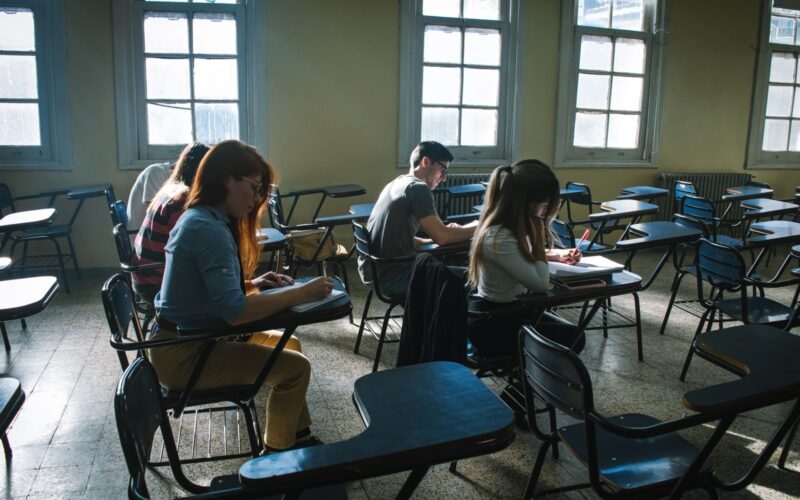 A group of students focused on taking a test in a sunlit classroom setting.