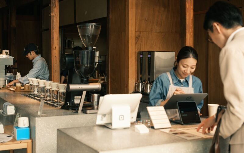 Barista and customers in a cozy Japanese coffee shop, showcasing a modern cafe atmosphere.