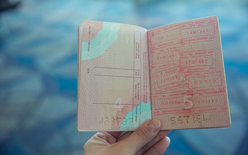 Close-up view of an open passport displaying various travel stamps in an airport setting.