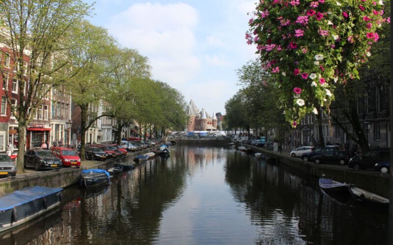 Beautiful Amsterdam canal view with flowers and historic architecture on a bright spring day.