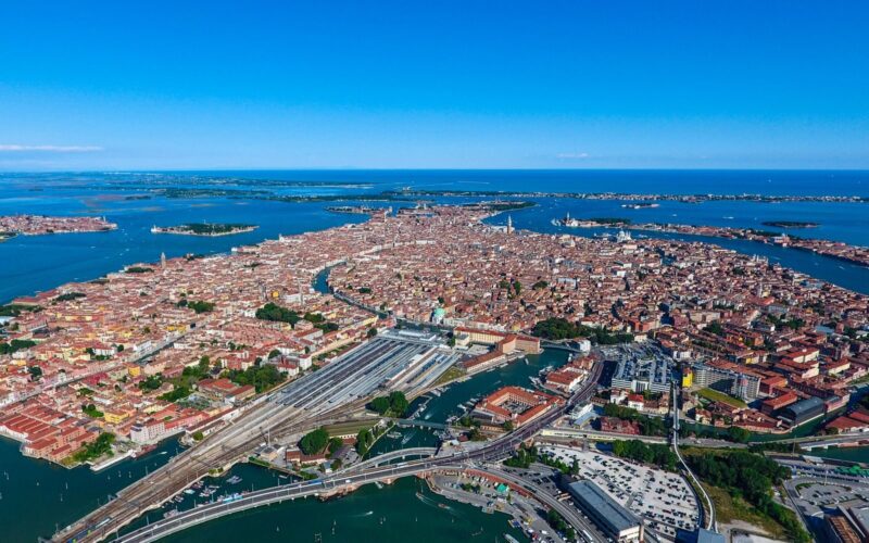 Stunning aerial photograph capturing the iconic cityscape of Venice surrounded by blue waters on a sunny day.