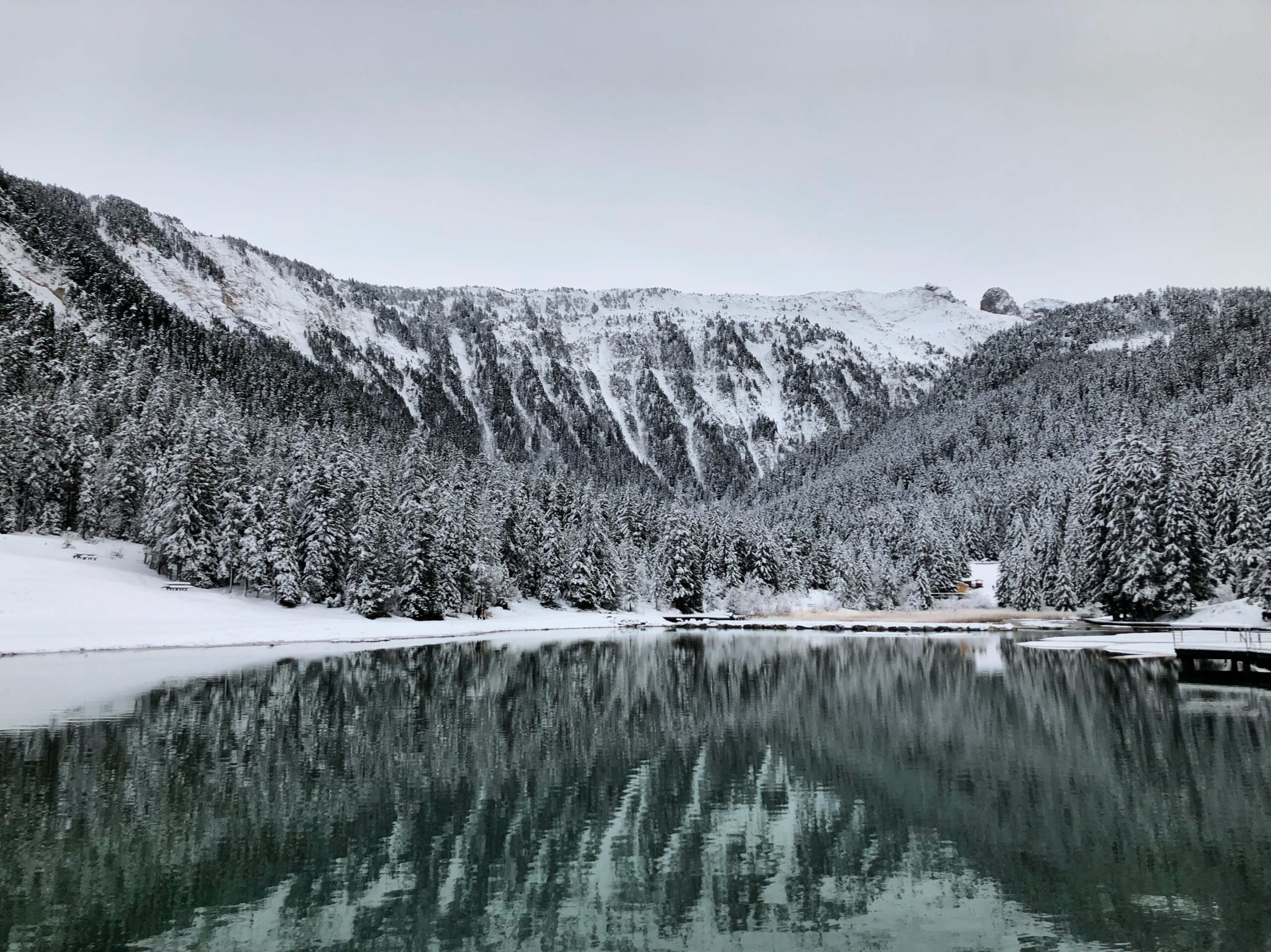 Courchevel'de kışın karla kaplı dağlar ve sakin göl manzarası