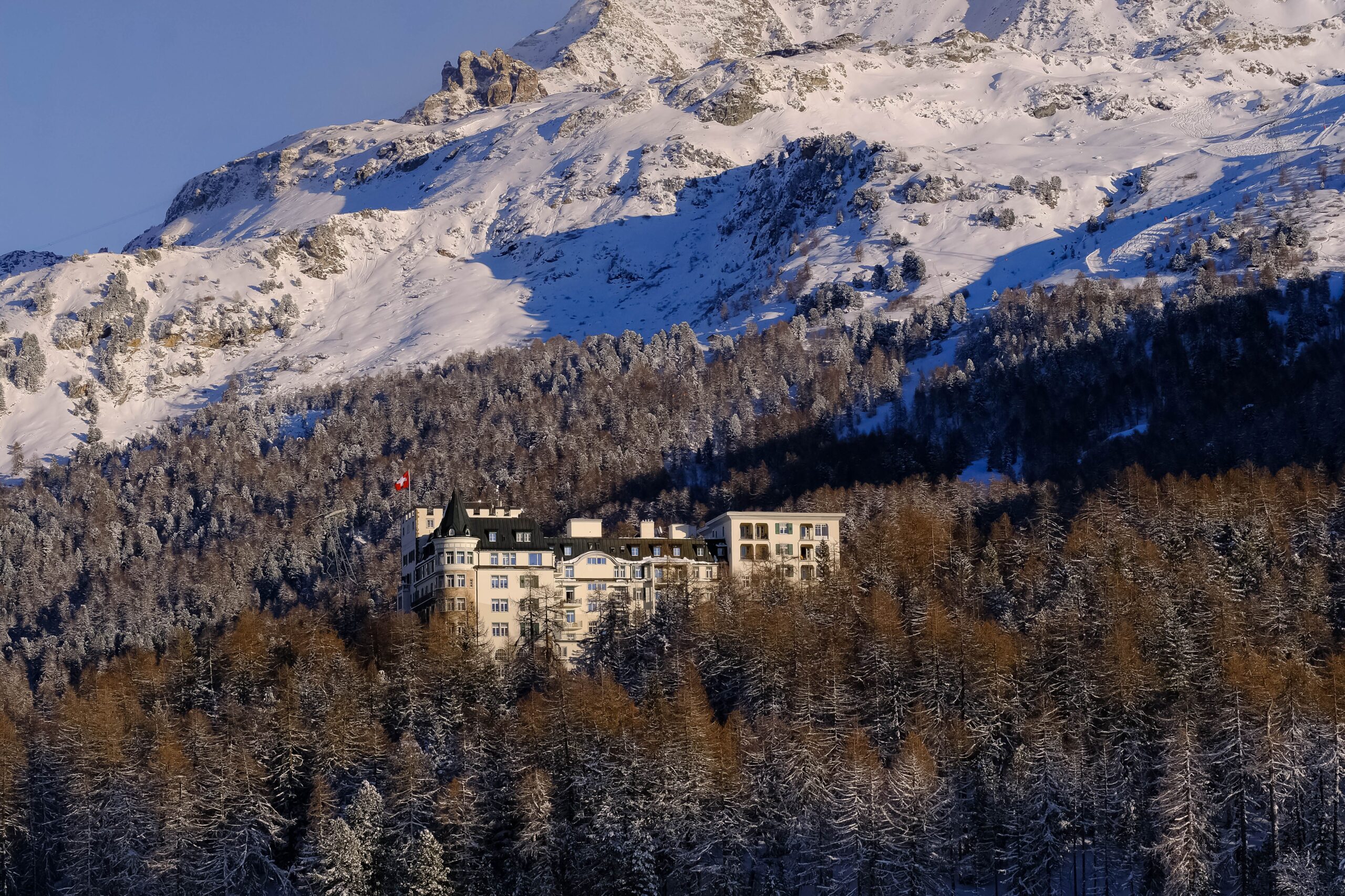St. Moritz'te karla kaplı dağların eteklerinde tarihi oteller ve kış manzarası