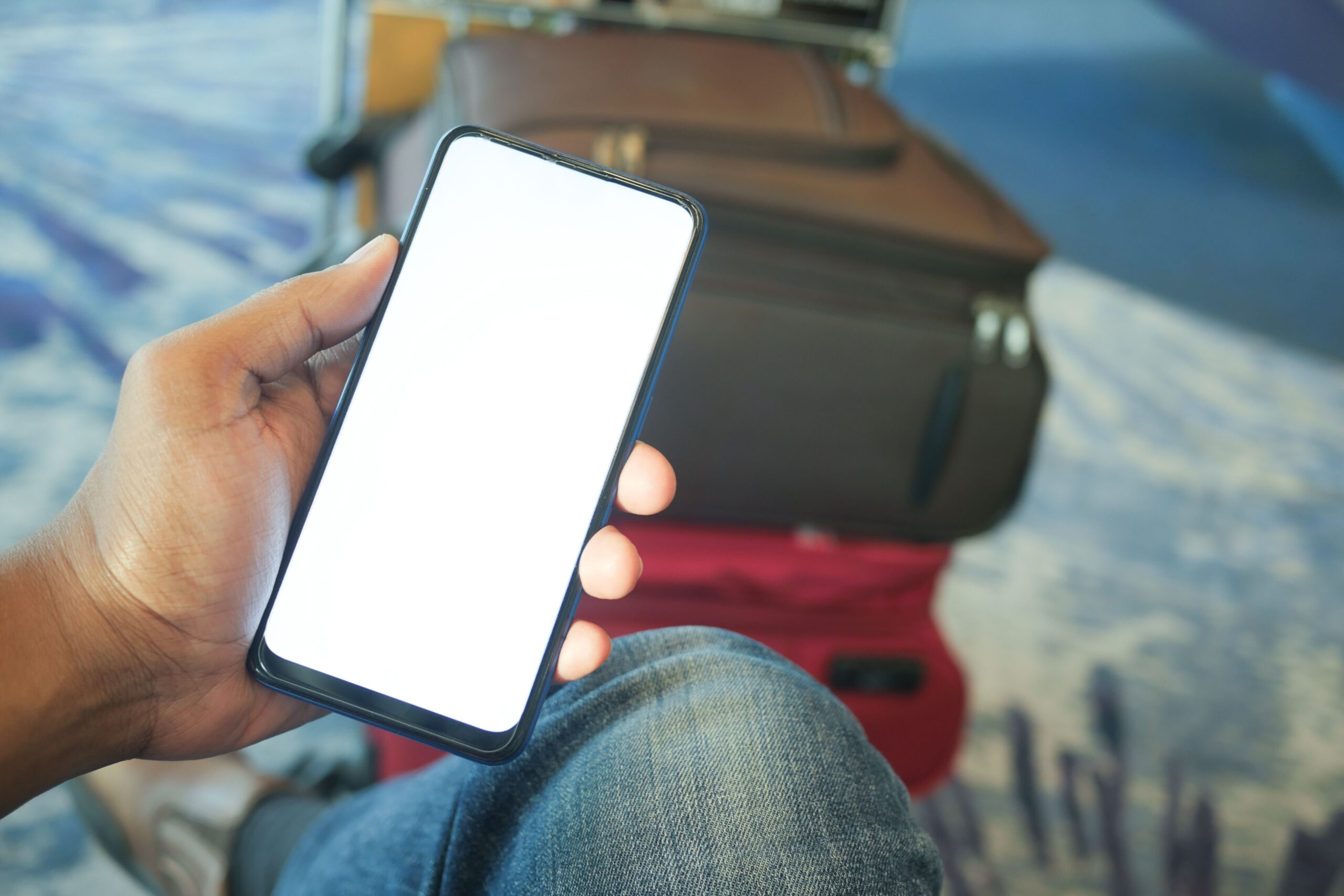 Havalimanında valizinin yanında akıllı telefon kullanan gezgin