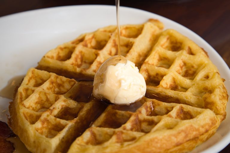 Üzerinde çikolata sosu ve meyve bulunan altın renkli waffle