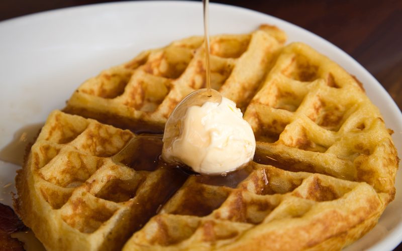 Üzerinde çikolata sosu ve meyve bulunan altın renkli waffle