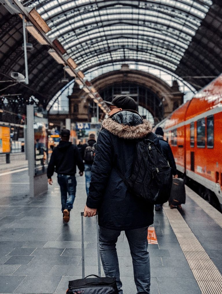 Tren istasyonunda sırt çantası ve valiziyle bekleyen gezgin