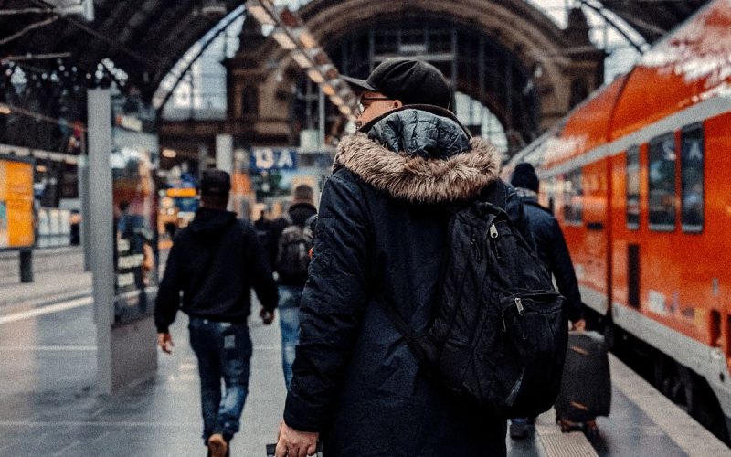 Tren istasyonunda sırt çantası ve valiziyle bekleyen gezgin