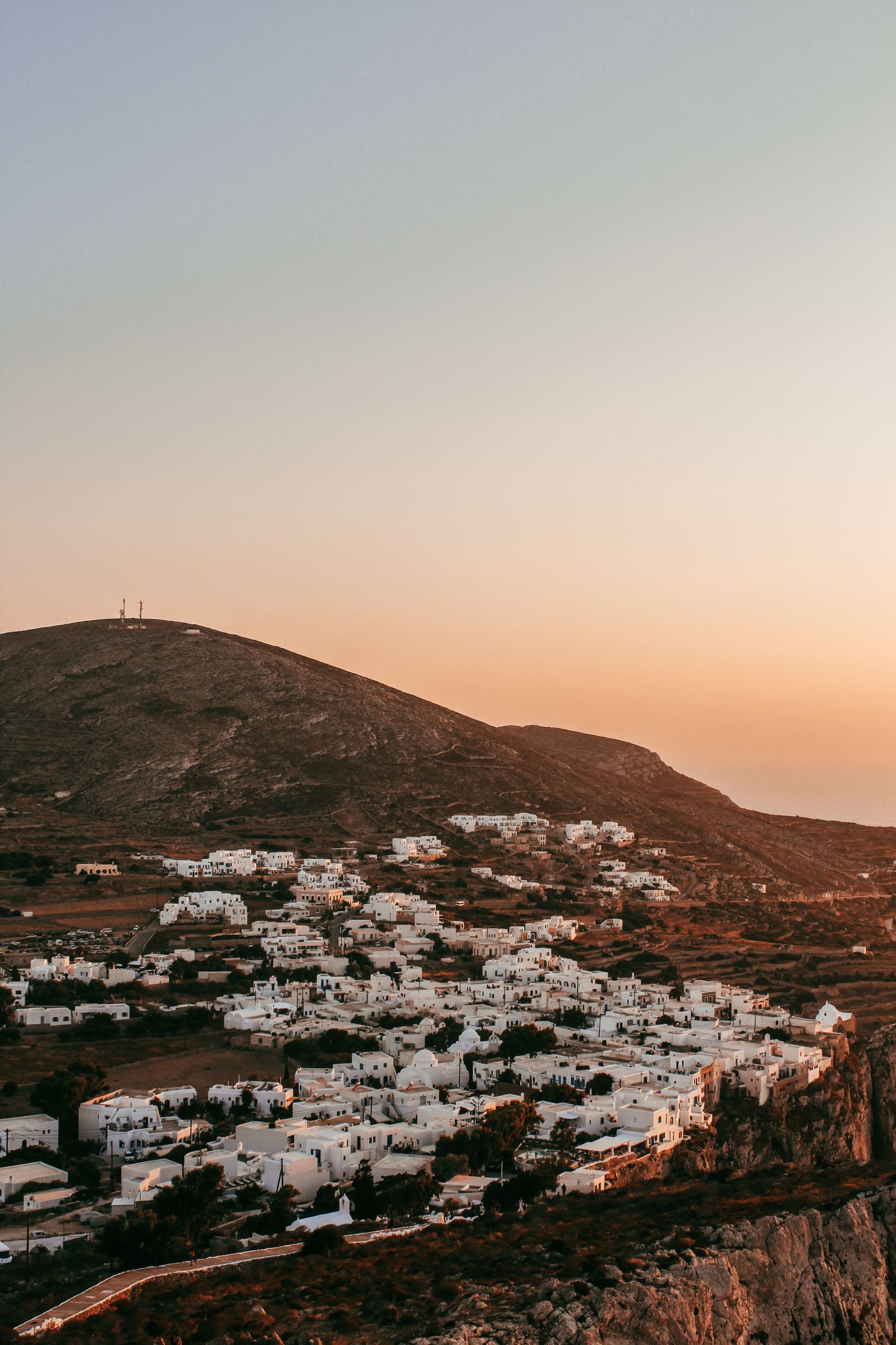 Folegandros'ta gün batımında kayalık yamaca kurulu beyaz evler