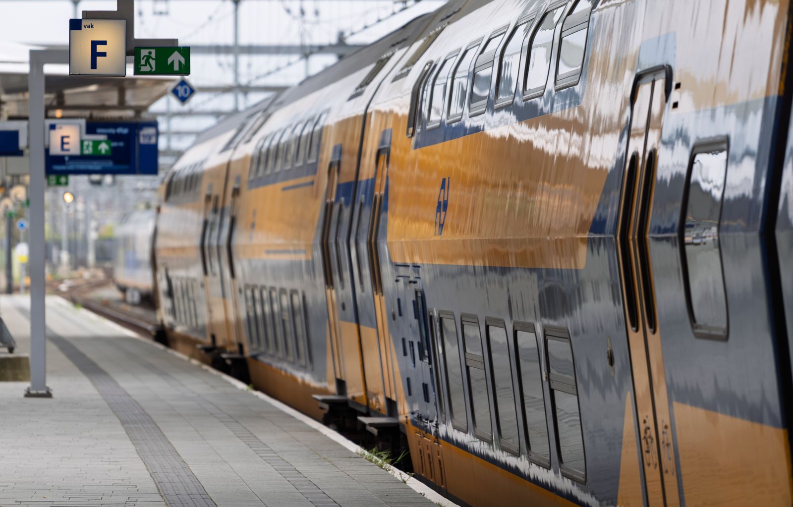 Hollanda’daki bir istasyon peronunda bekleyen sarı-mavi yolcu treni