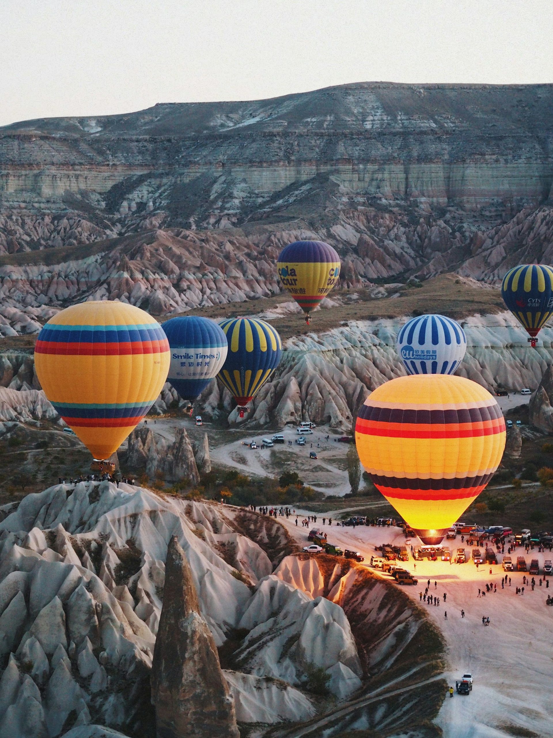 Göreme vadisinde kayalık yamaçların üzerinde süzülen sıcak hava balonları
