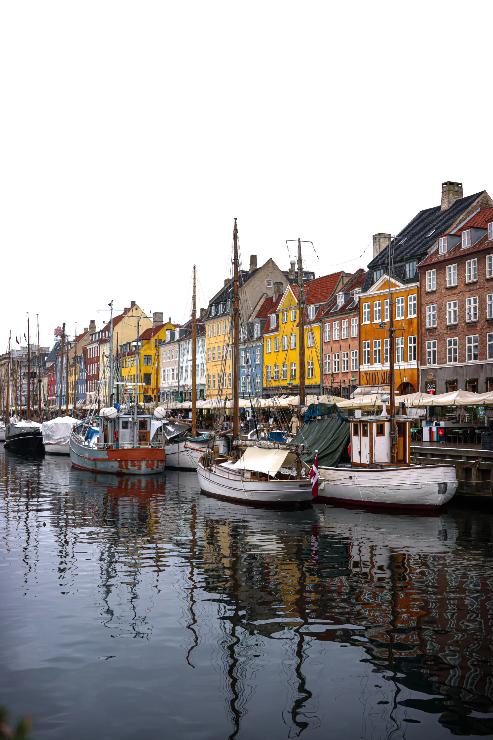 Kopenhag Nyhavn kanalında renkli tarihî evler ve kıyıya bağlı tekneler