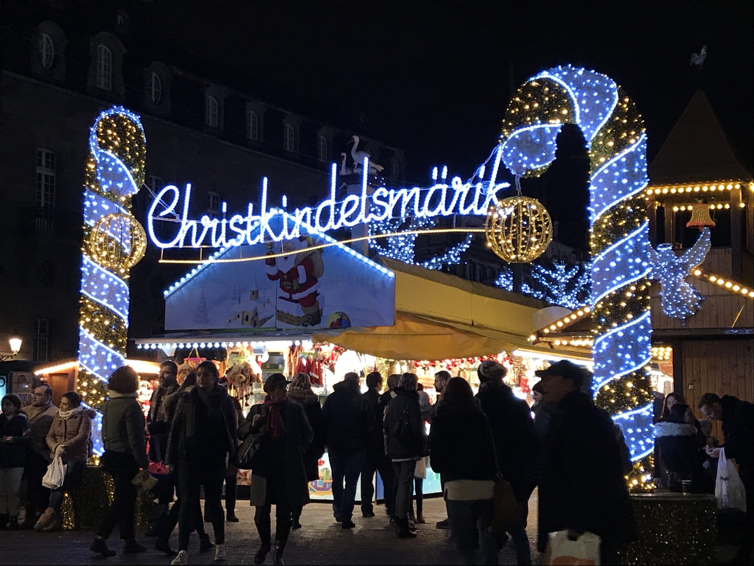 Strasbourg Christkindelsmärik Noel pazarı, ışıklı giriş süslemeleri ve ahşap tezgâhlar