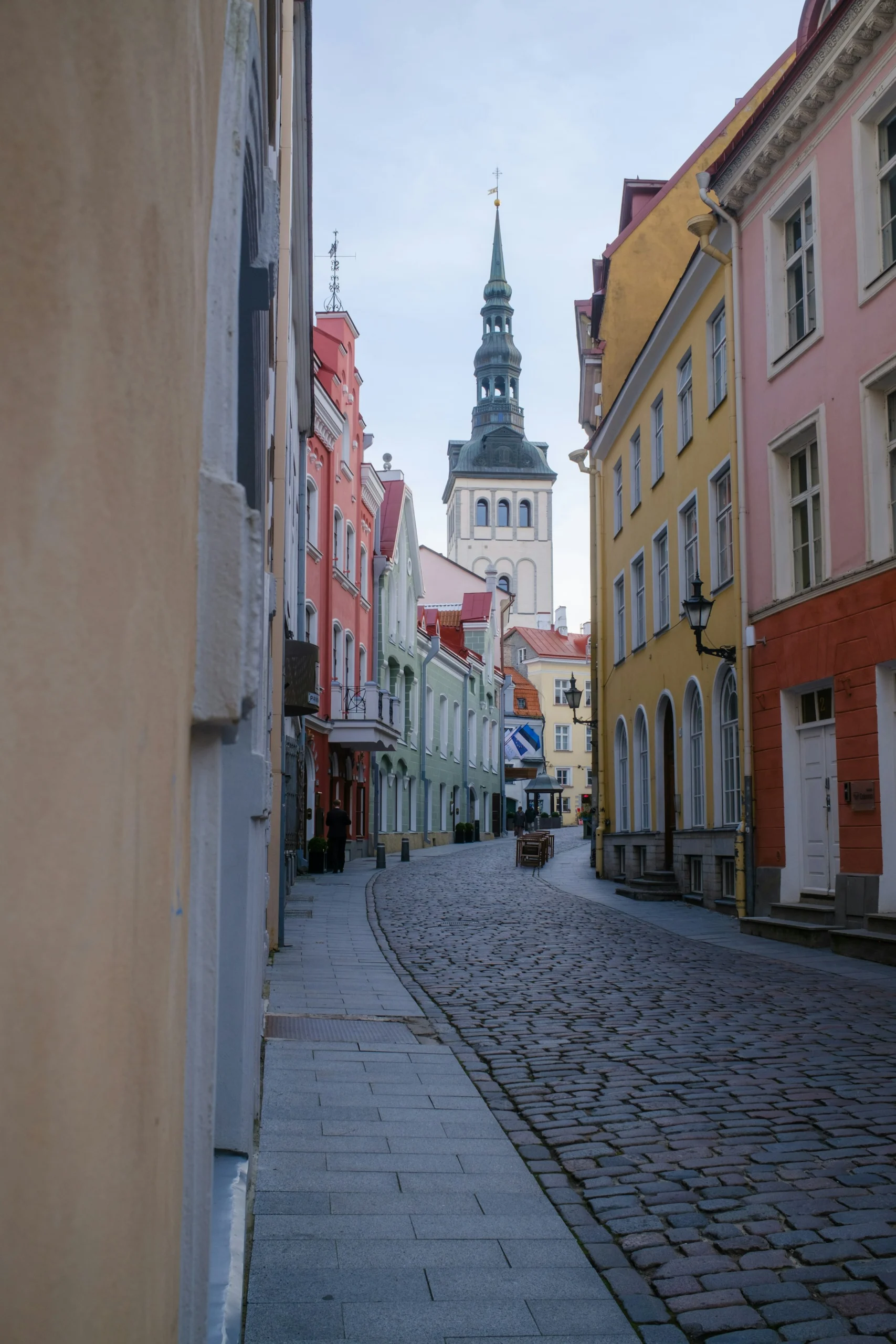 Tallinn Eski Şehir’de renkli tarihî binalar, taş döşeli sokak ve kilise kulesi