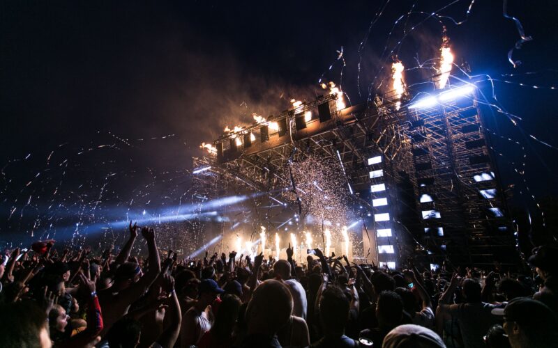 Açık havada kalabalık bir müzik festivalinde sahne ve izleyiciler