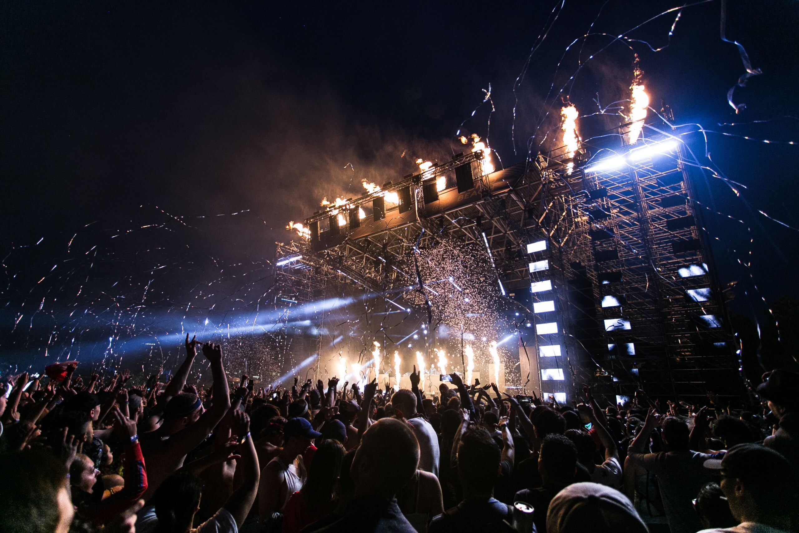 Açık havada kalabalık bir müzik festivalinde sahne ve izleyiciler
